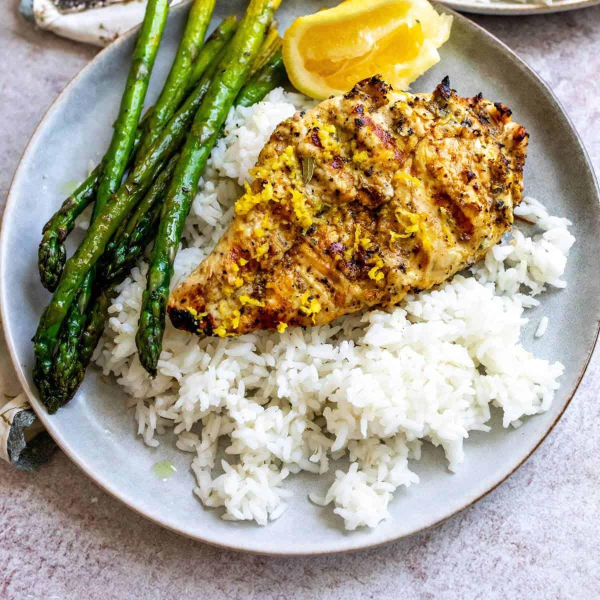 a bowl of lemon pepper rice next to grilled chicken