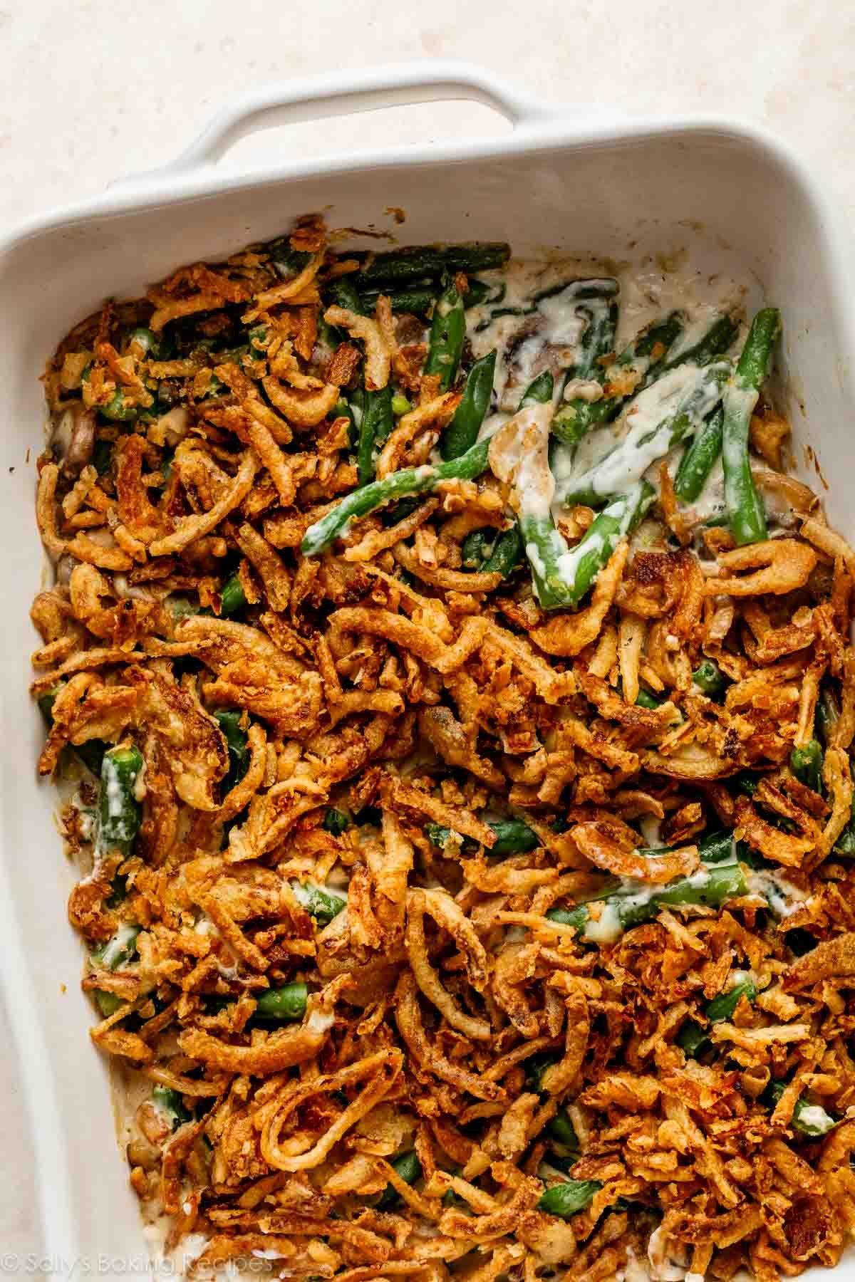 Close-up of green bean casserole with a rich, bubbling gravy, topped with golden crispy onions