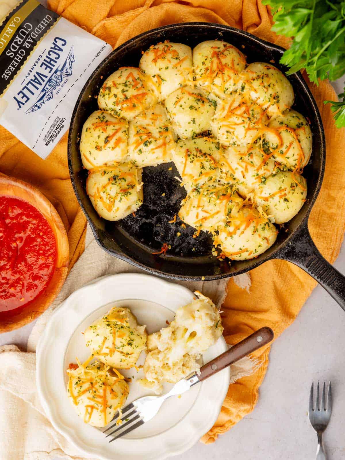 overhead shot of a platter of cheesy garlic bread bites with fresh herbs