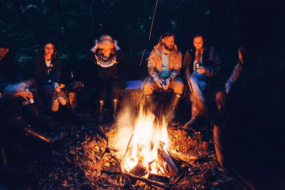 group of friends around a bonfire eating pizza