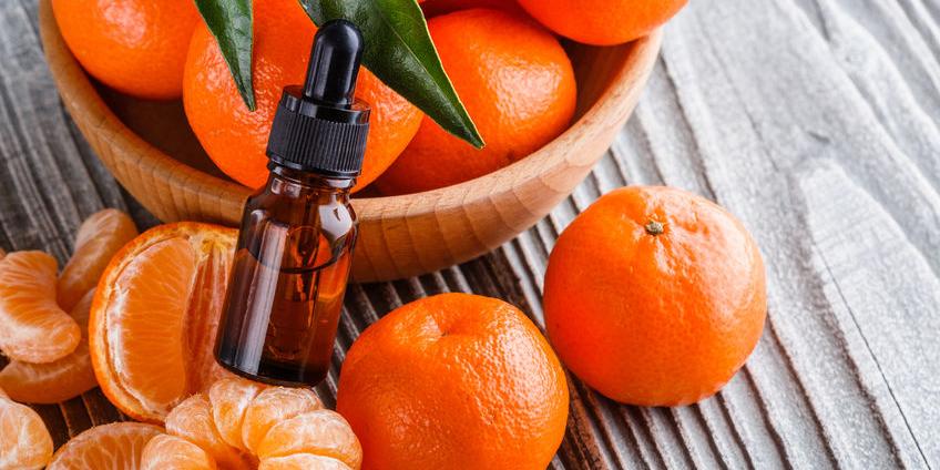 close up of tangerine essential oil being poured into a diffuser