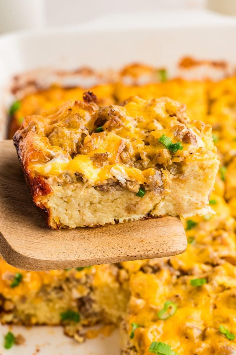 close-up of a slice of pancake sausage and egg casserole being lifted from the dish, showing the layers