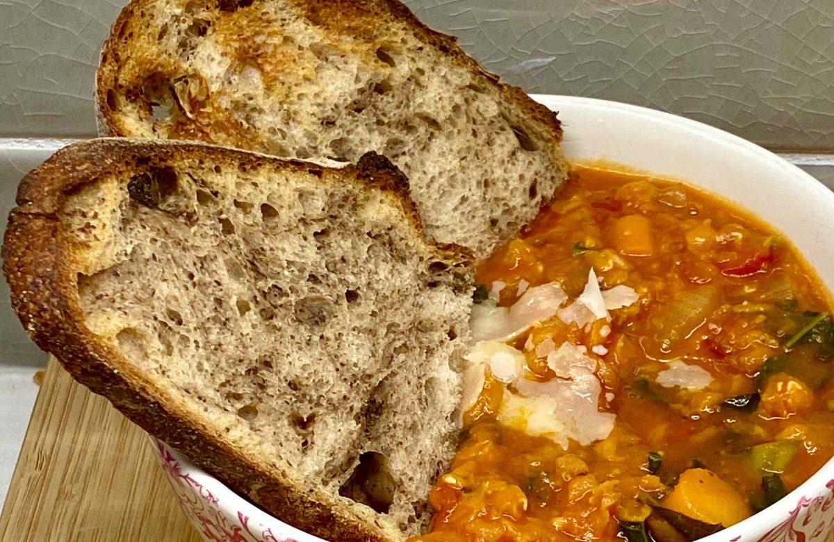 Rustic bowl of steaming lentil vegetable stew with crusty bread