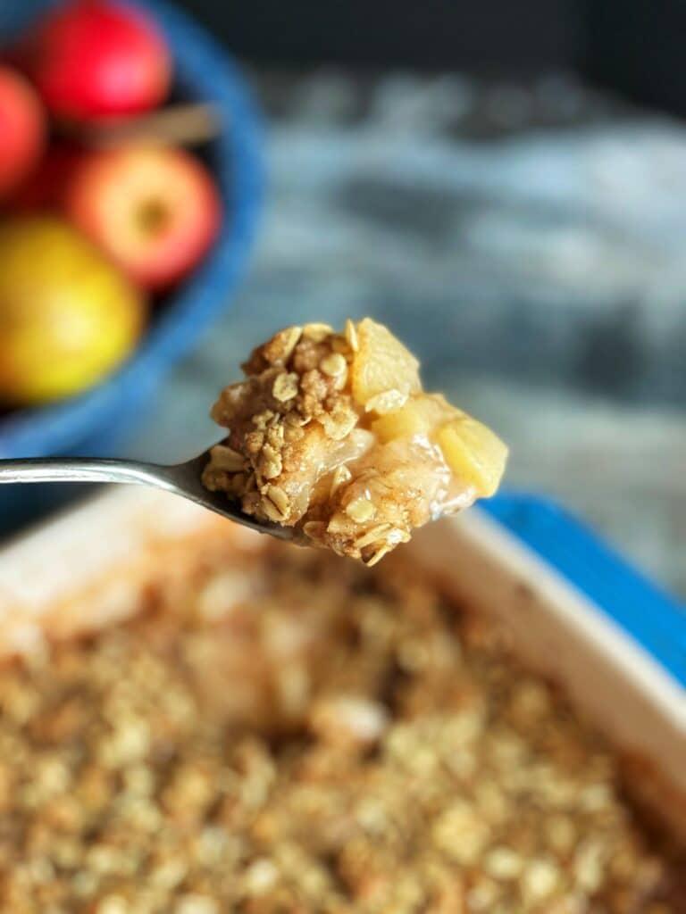Close-up shot of a spoonful of apple crisp, showcasing the texture and color