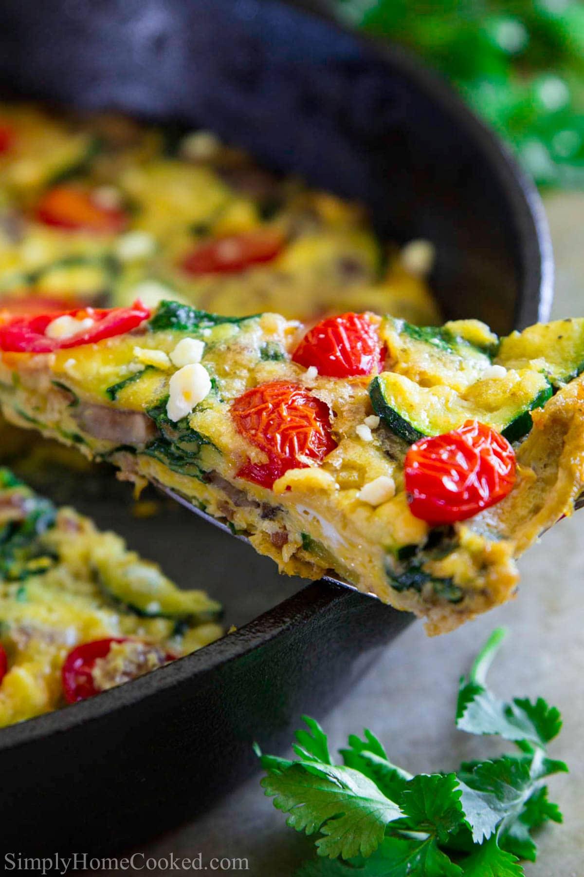 Close-up of a slice of frittata being lifted from a skillet.