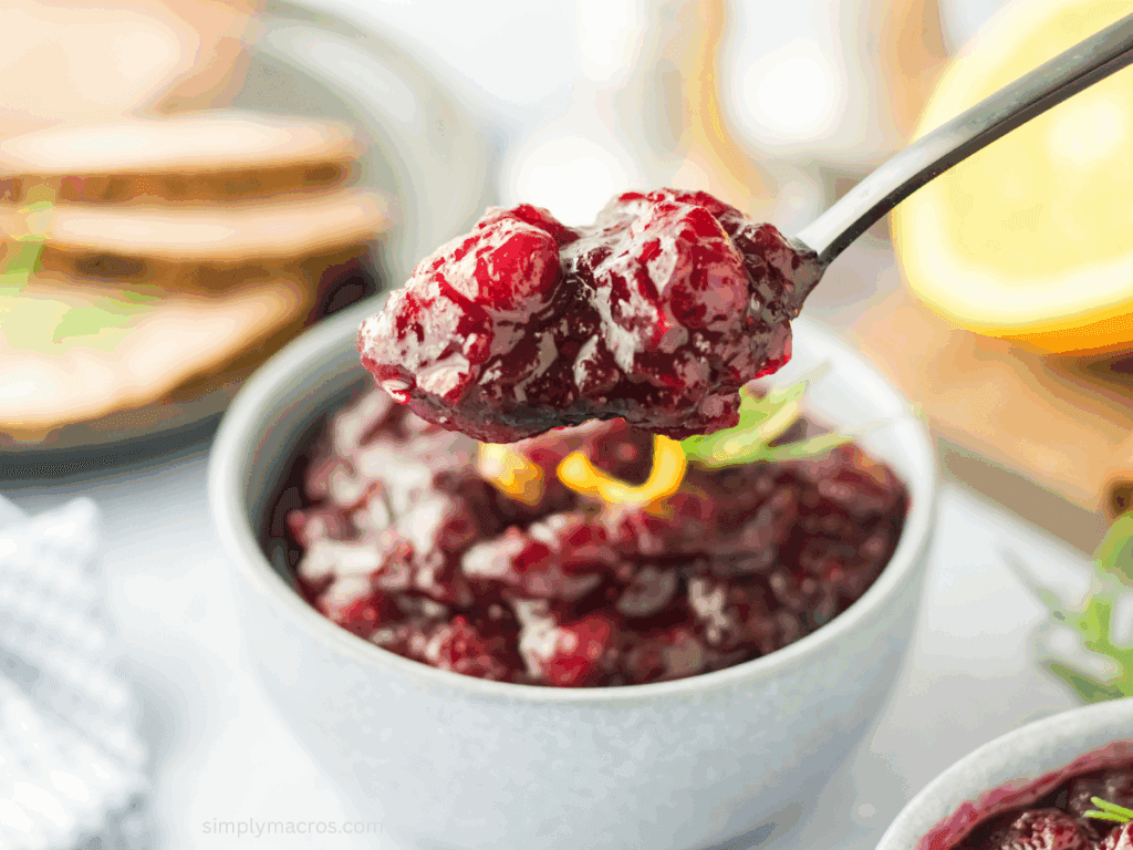 Spoon scooping perfectly set ruby cranberry sauce from a serving bowl