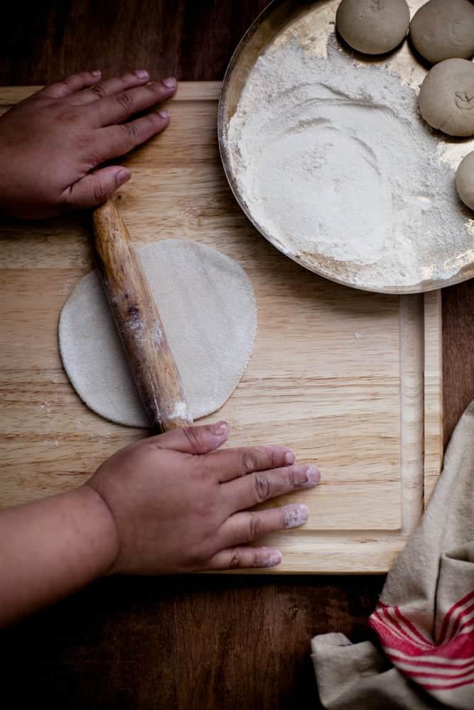 hand preparing homemade roti dough on a floured surface