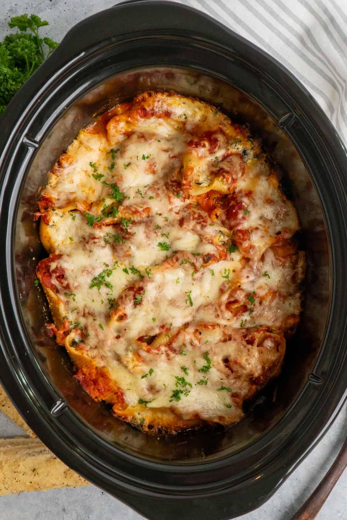 stuffed shells being arranged in a slow cooker