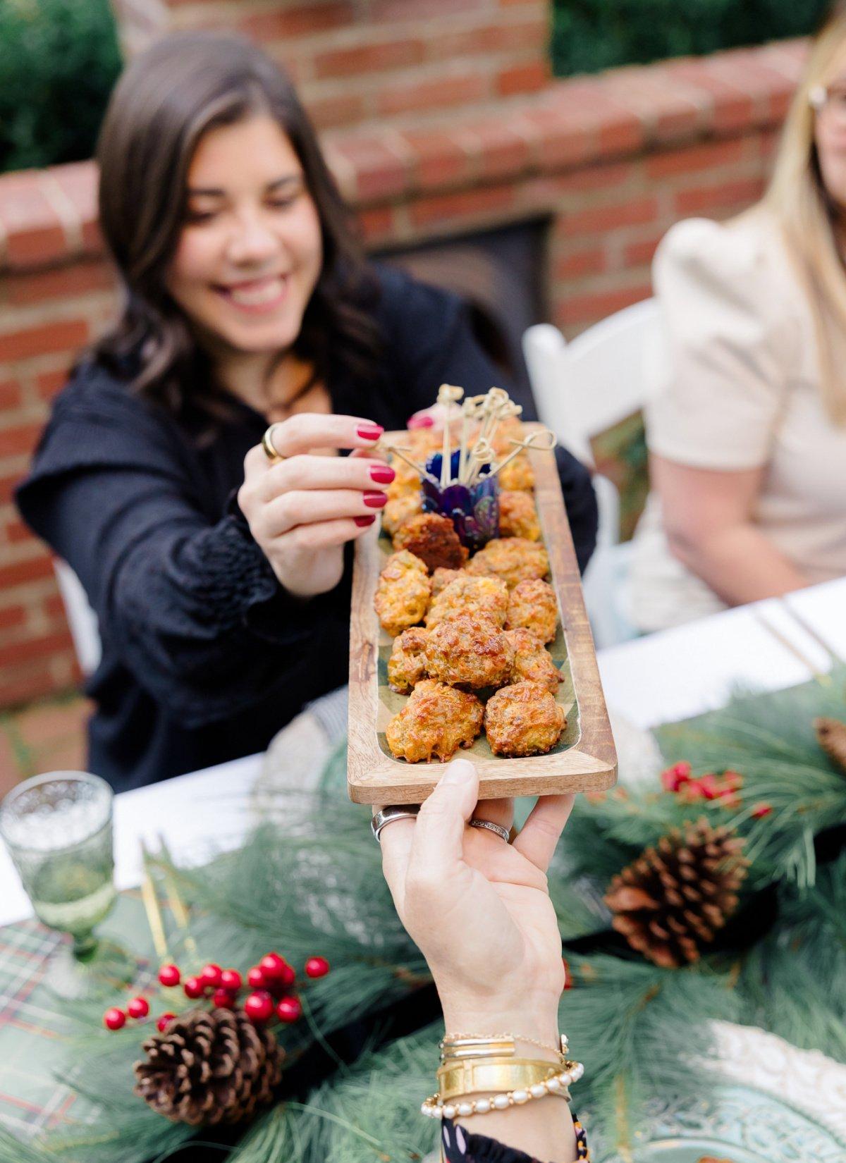 Smiling family members at a brunch table, reaching for a platter of sausage balls