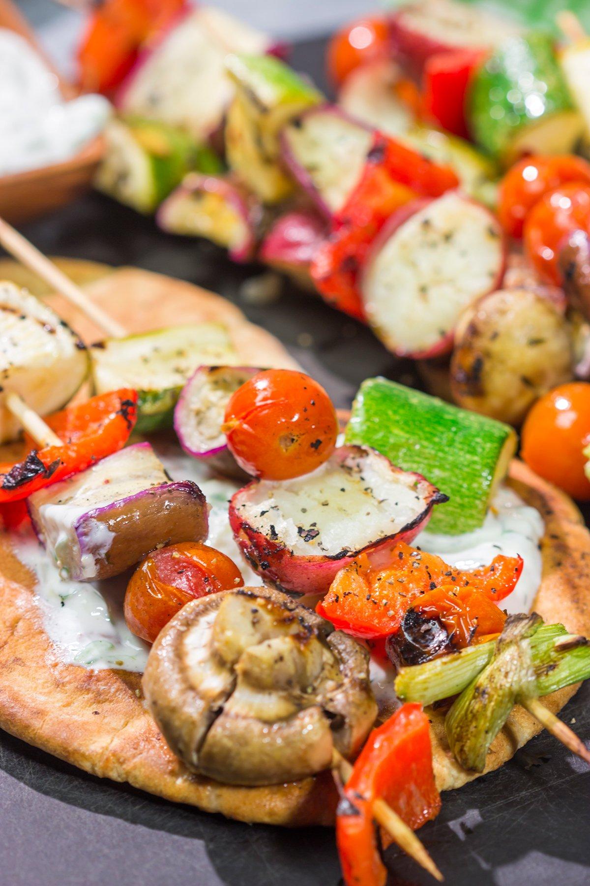 Close up shot of someone holding a perfectly grilled vegetable souvlaki skewer