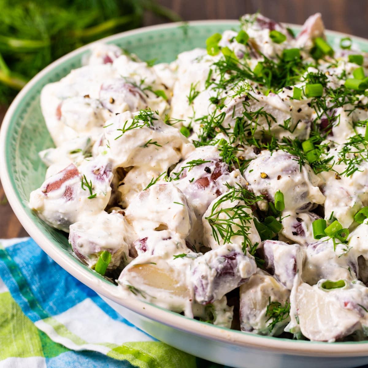 Bowl of creamy dill potato salad served alongside grilled chicken