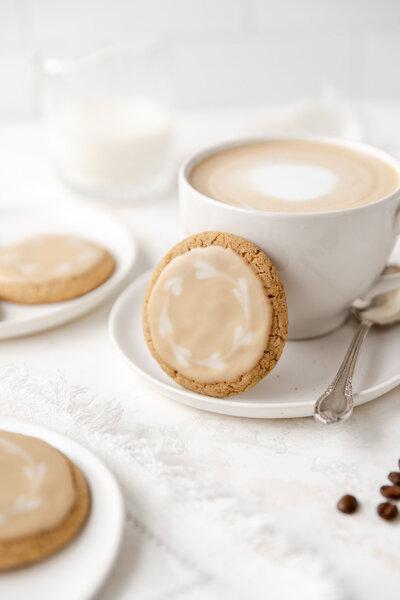 Overhead shot of several vanilla crumb sugar cookies arranged on a white plate with a cup of coffee