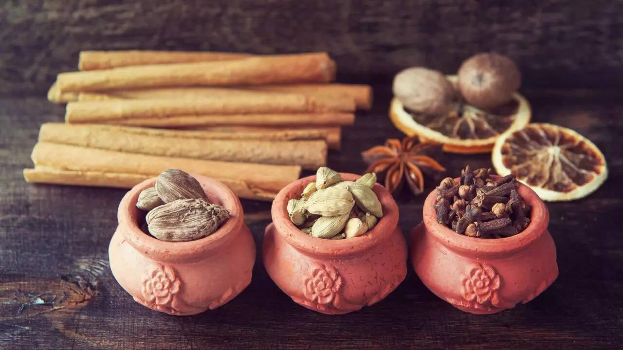 Aromatic spices like cardamom, cumin, and turmeric arranged on a rustic wooden surface