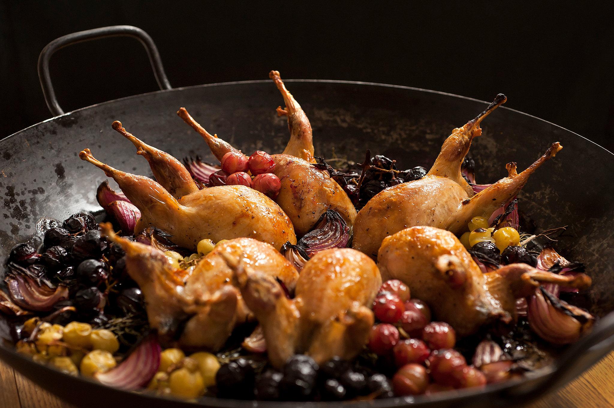 roasted quail with grape sauce on a rustic wooden table