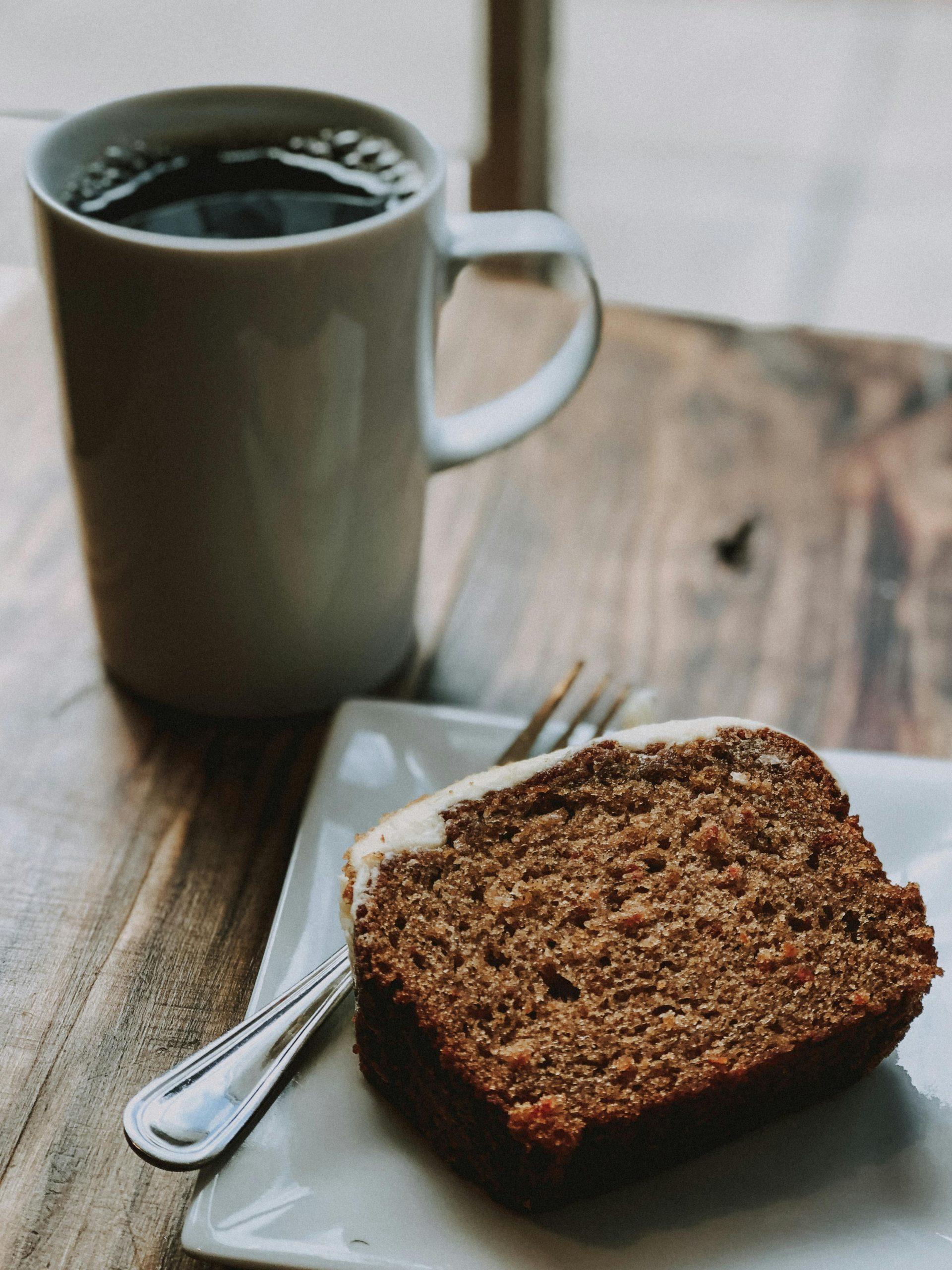 A slice of caramel banana bread on a rustic wooden board with a cup of coffee