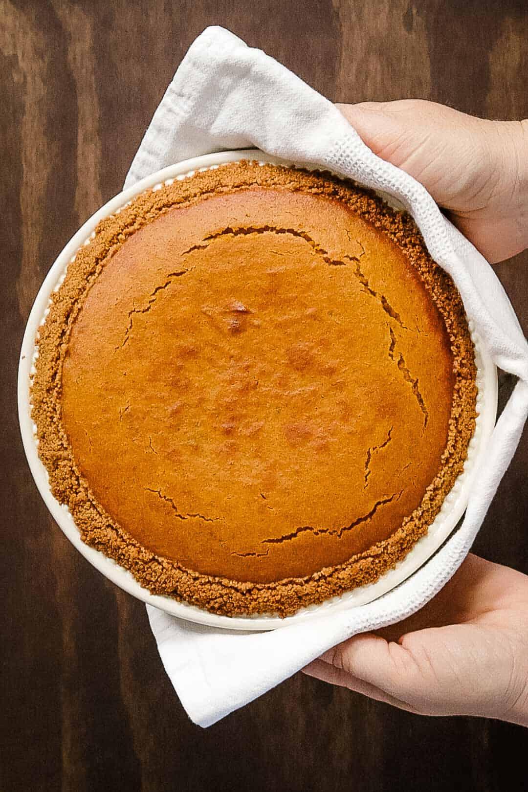 overhead shot of a golden-brown pumpkin pie cooling on a wire rack, with steam gently rising