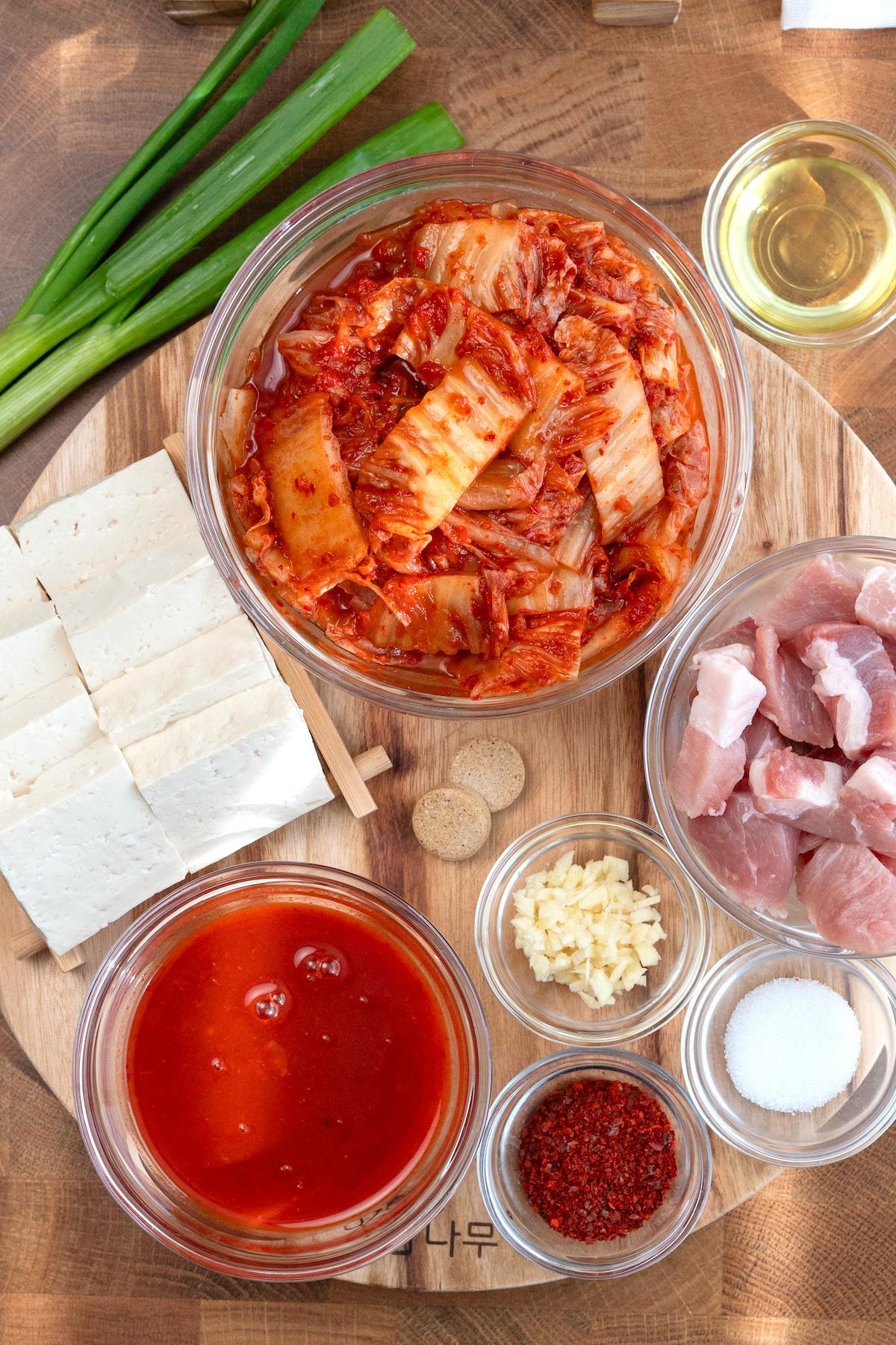 Ingredients for kimchi jjigae laid out on a wooden table