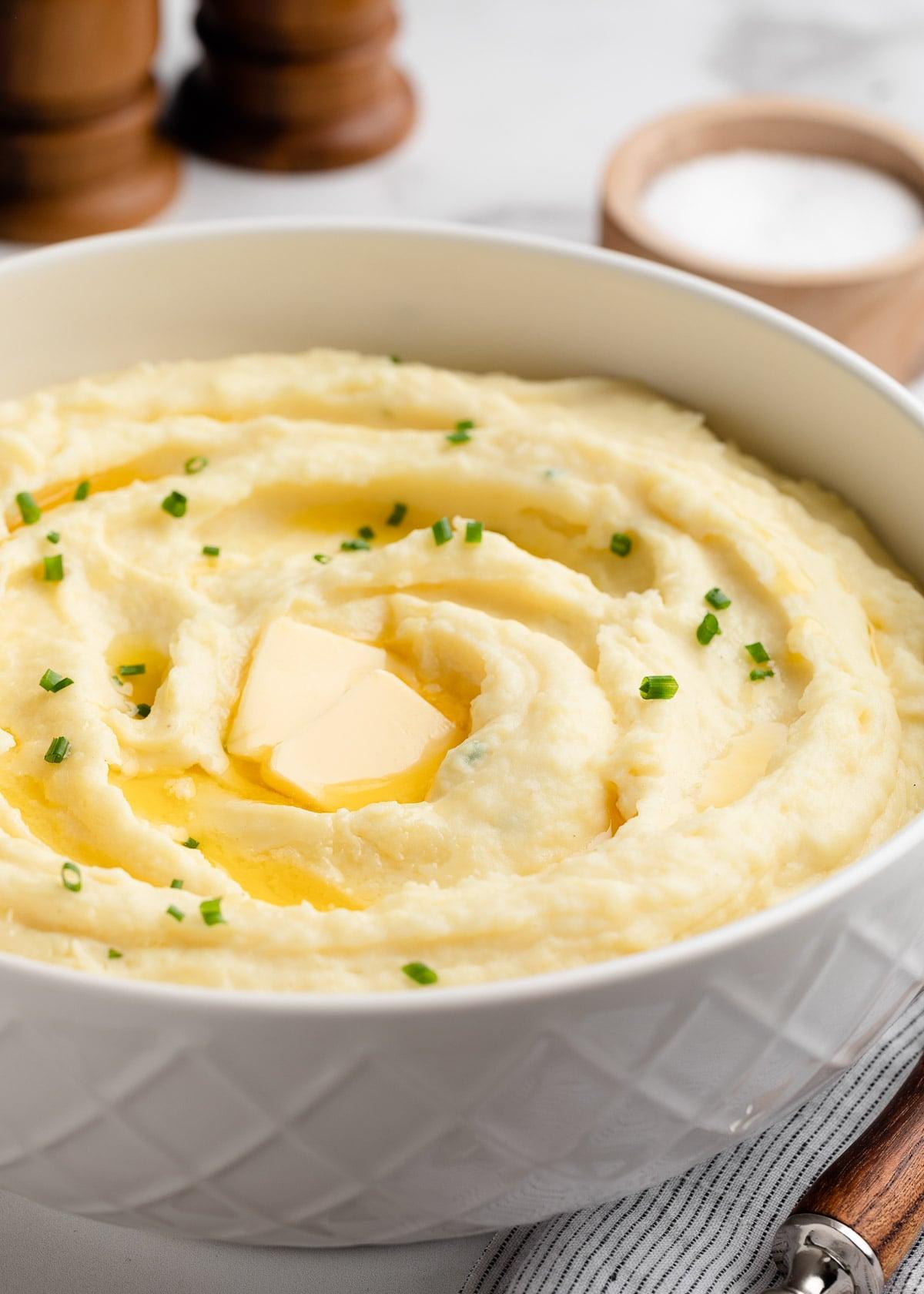 Someone happily taking a spoonful of creamy mashed potatoes from a serving bowl, blurry background