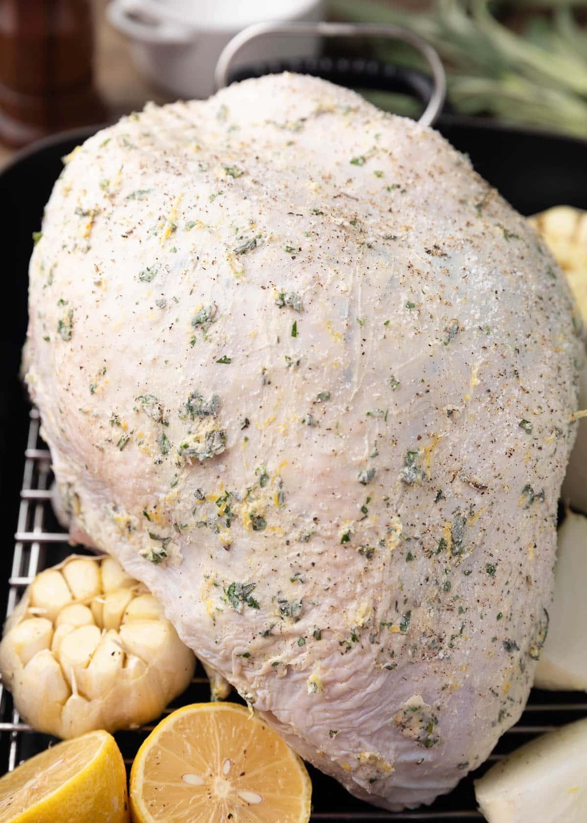 close-up of raw turkey breast being rubbed with herb butter