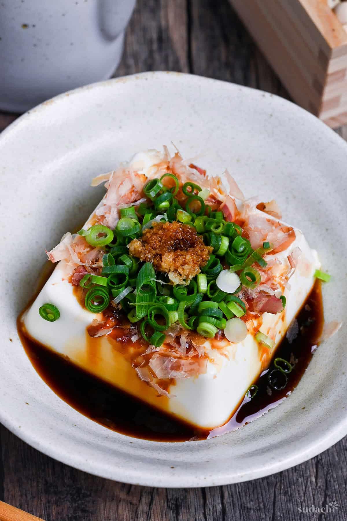 Close-up shot of a ginger soy glaze being drizzled over tofu