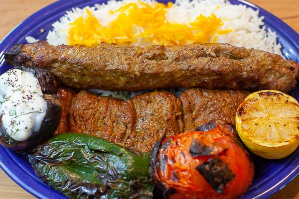 Overhead shot of Iranian Koobideh Beef Kebabs on a platter, surrounded by saffron rice and grilled vegetables