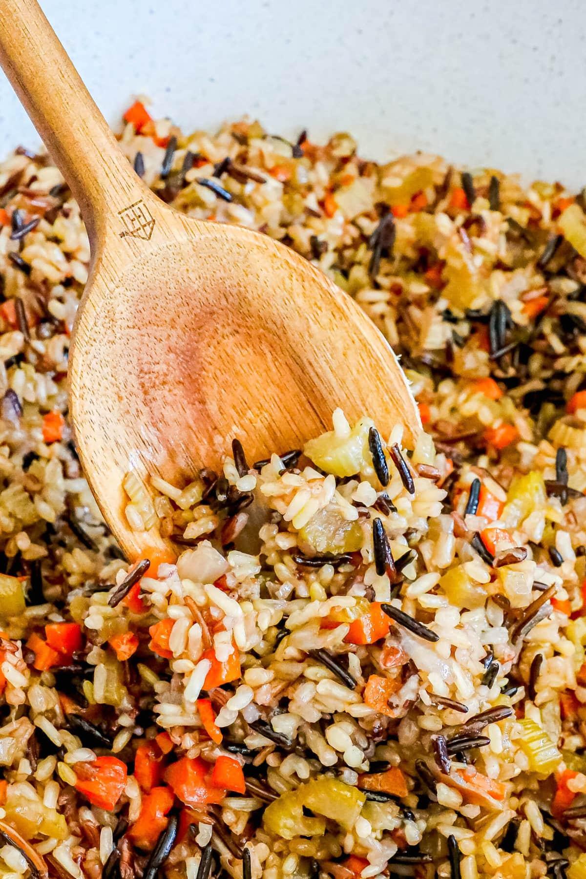 A rustic wooden table set with a plate of roasted chicken and wild rice pilaf