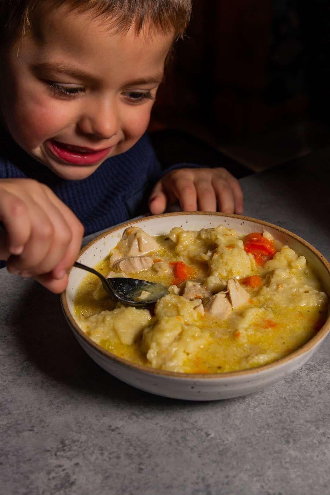 A person ladling a bowl of Instant Pot Chicken and Dumpling Soup with Thyme, with a warm, inviting atmosphere in the background.
