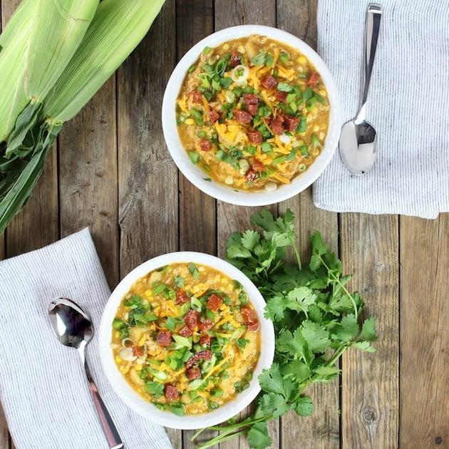 bowl of chicken corn chowder on a wooden table with a spoon