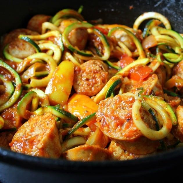 close up of a skillet with spicy sausage, peppers, and zoodles being cooked