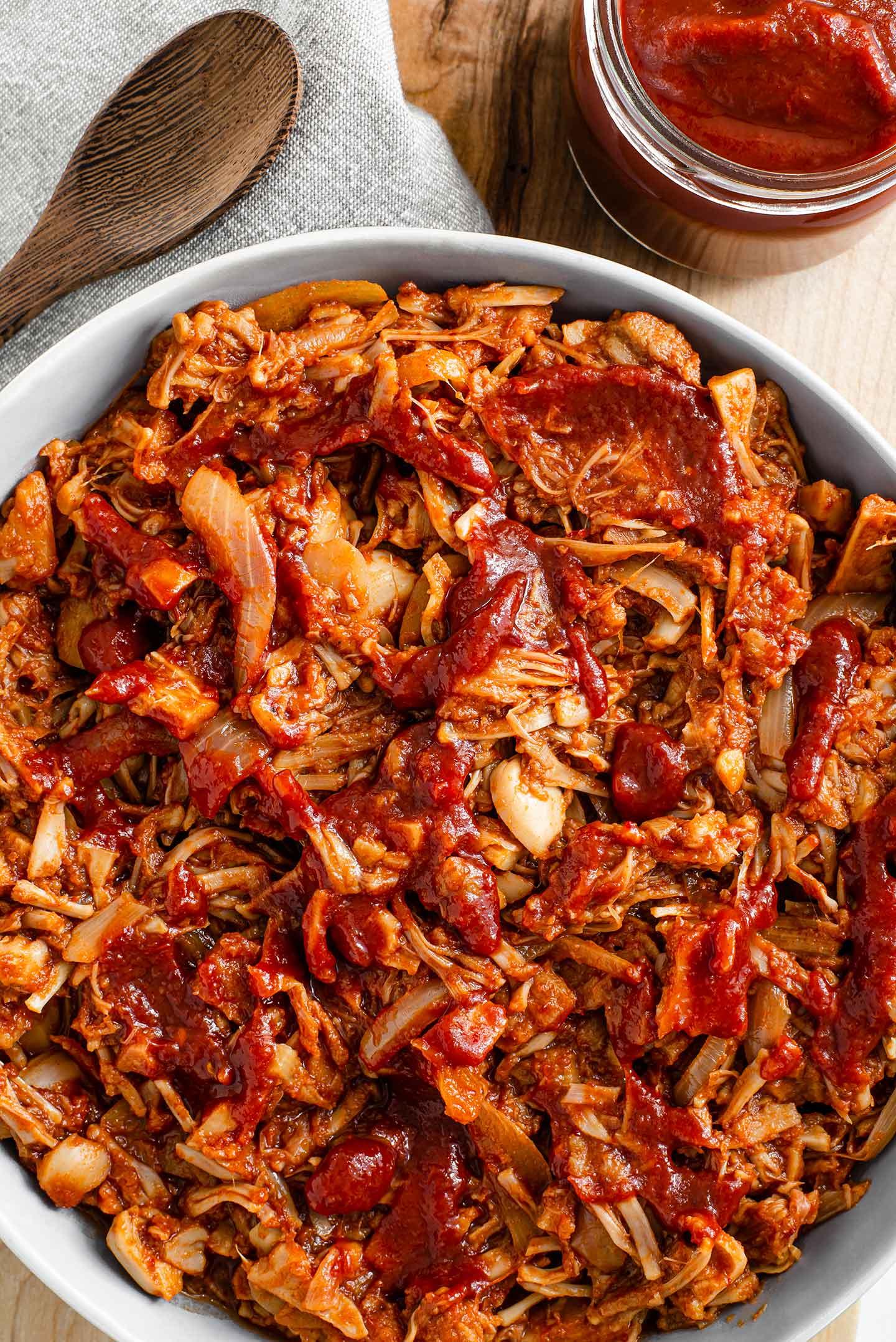 Close-up shot of shredded jackfruit in a skillet, coated in sweet chili sauce.