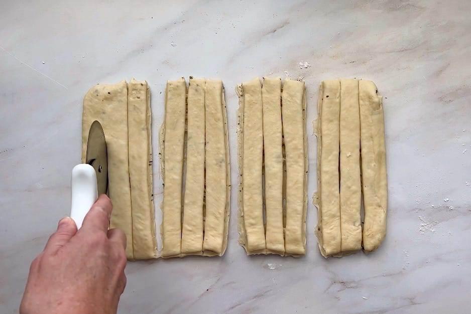 Rolled dough strips being tied into knots on a baking sheet