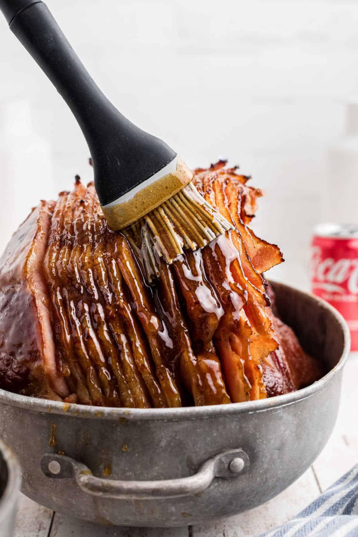 close up image of someone basting a ham with a glaze