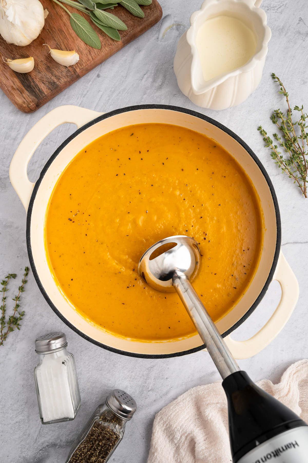overhead shot of pumpkin chive soup with a spoon taking a scoop