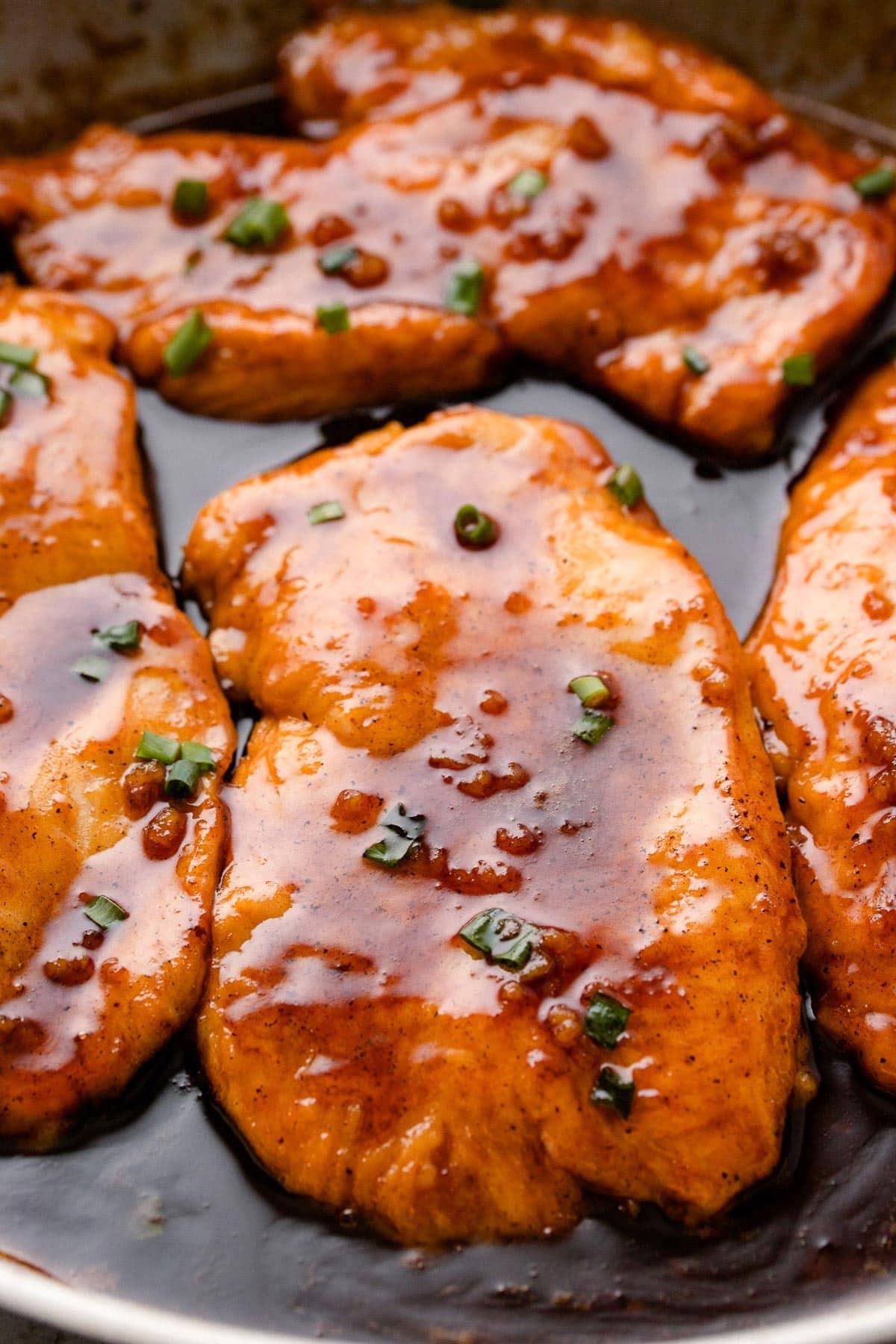 Close-up of golden brown honey garlic butter chicken in a skillet, glossy sauce