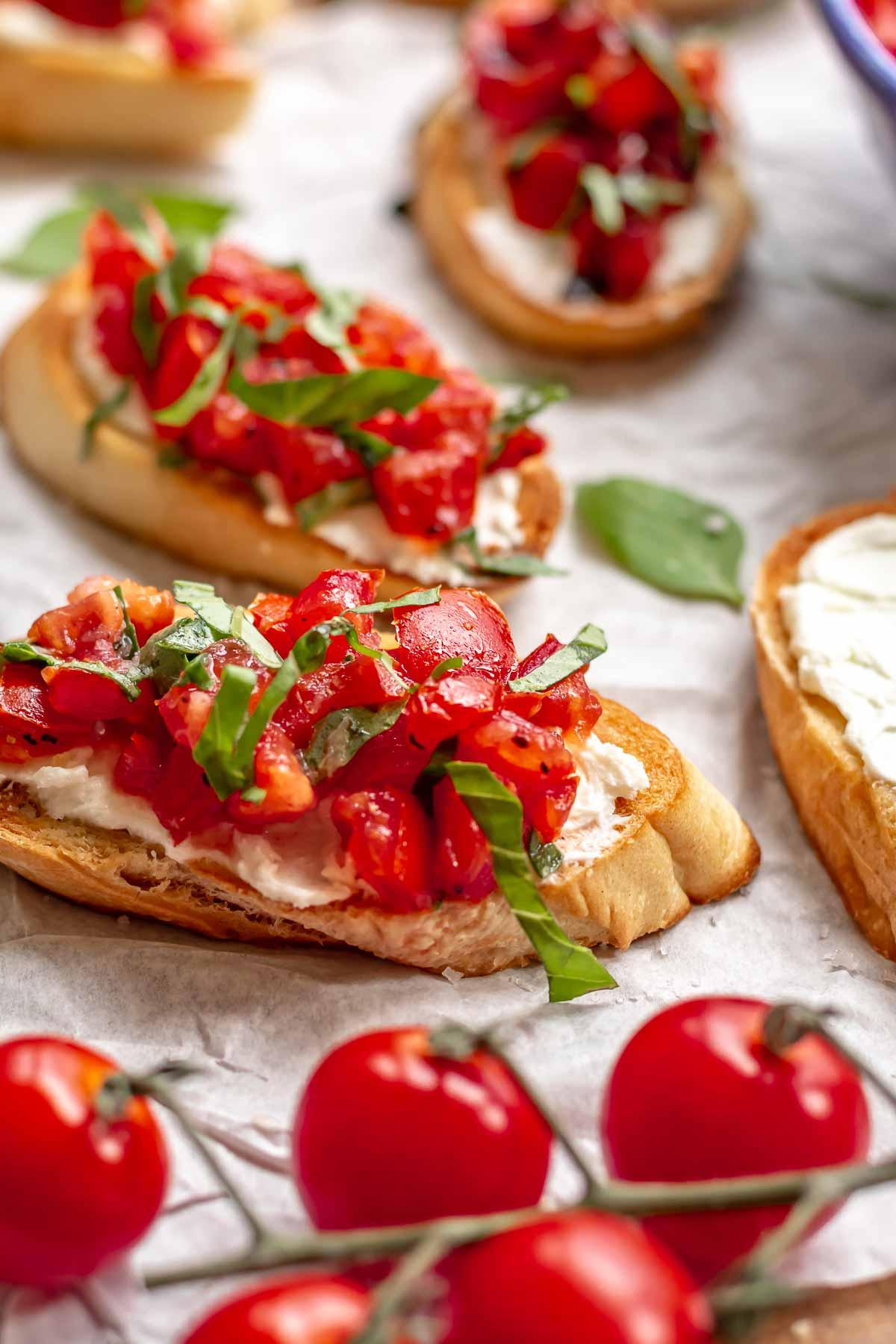 Whipped goat cheese being spread on a toasted baguette slice