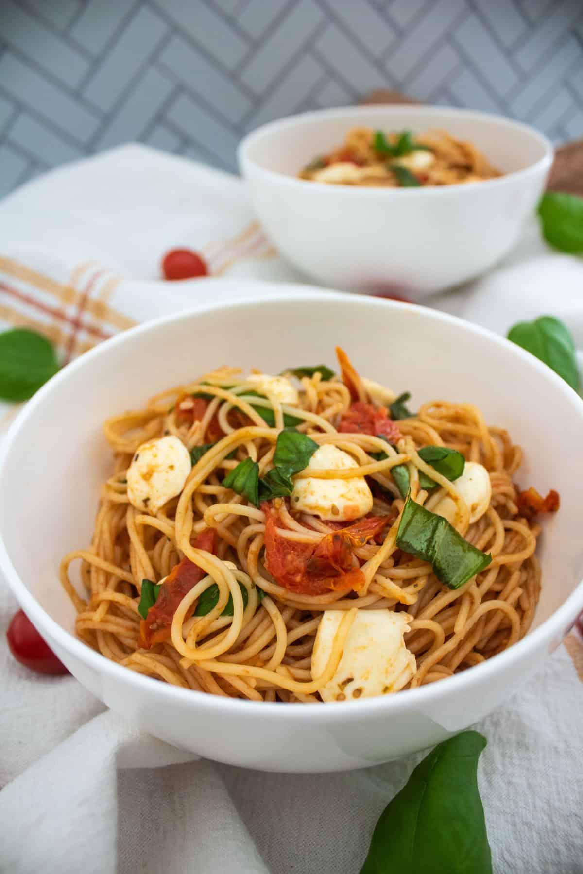 a skillet filled with simmering tomato basil sauce, with fresh basil leaves scattered on top