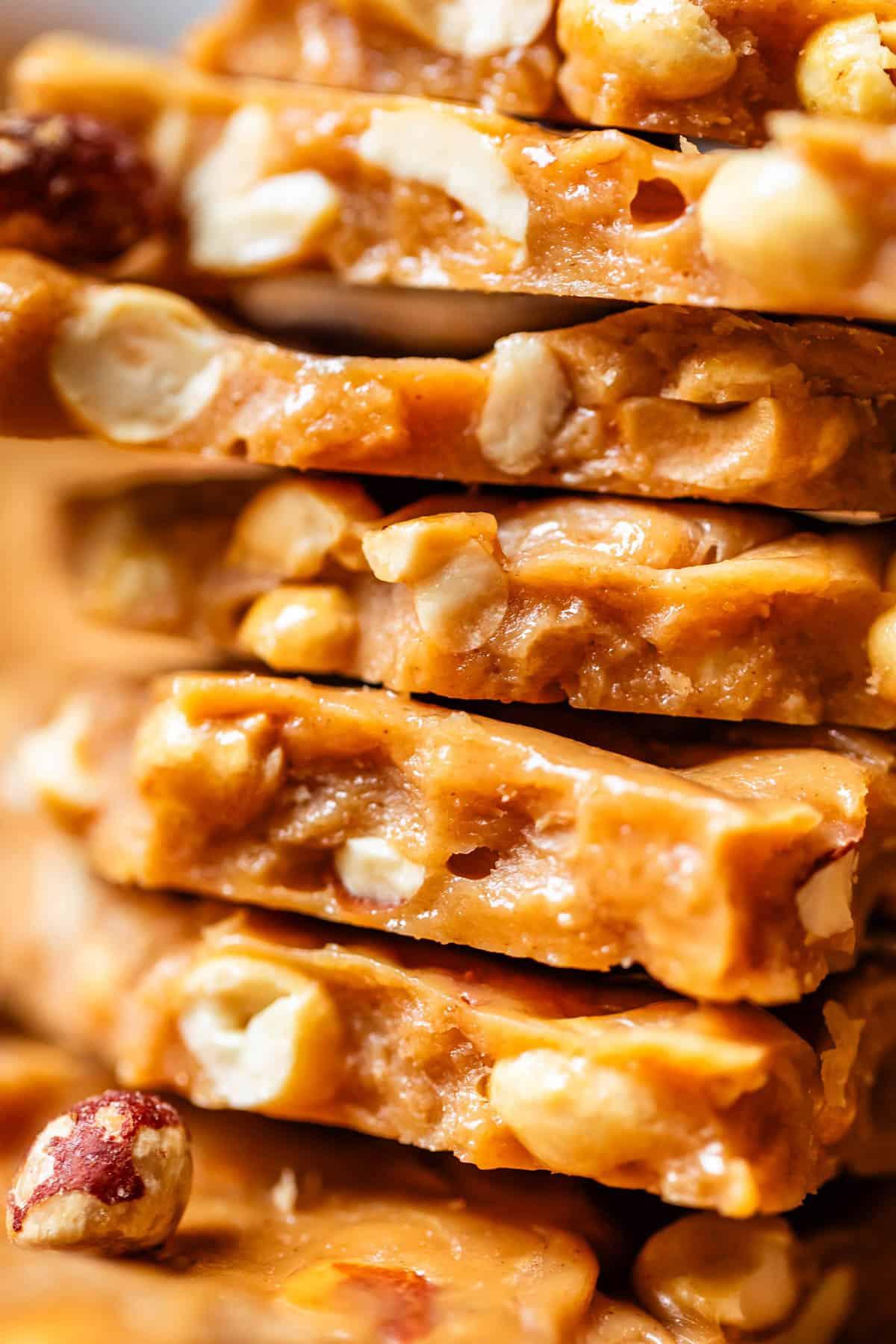 Glistening homemade peanut brittle cooling on a silicone mat, close-up, golden caramel with roasted peanuts