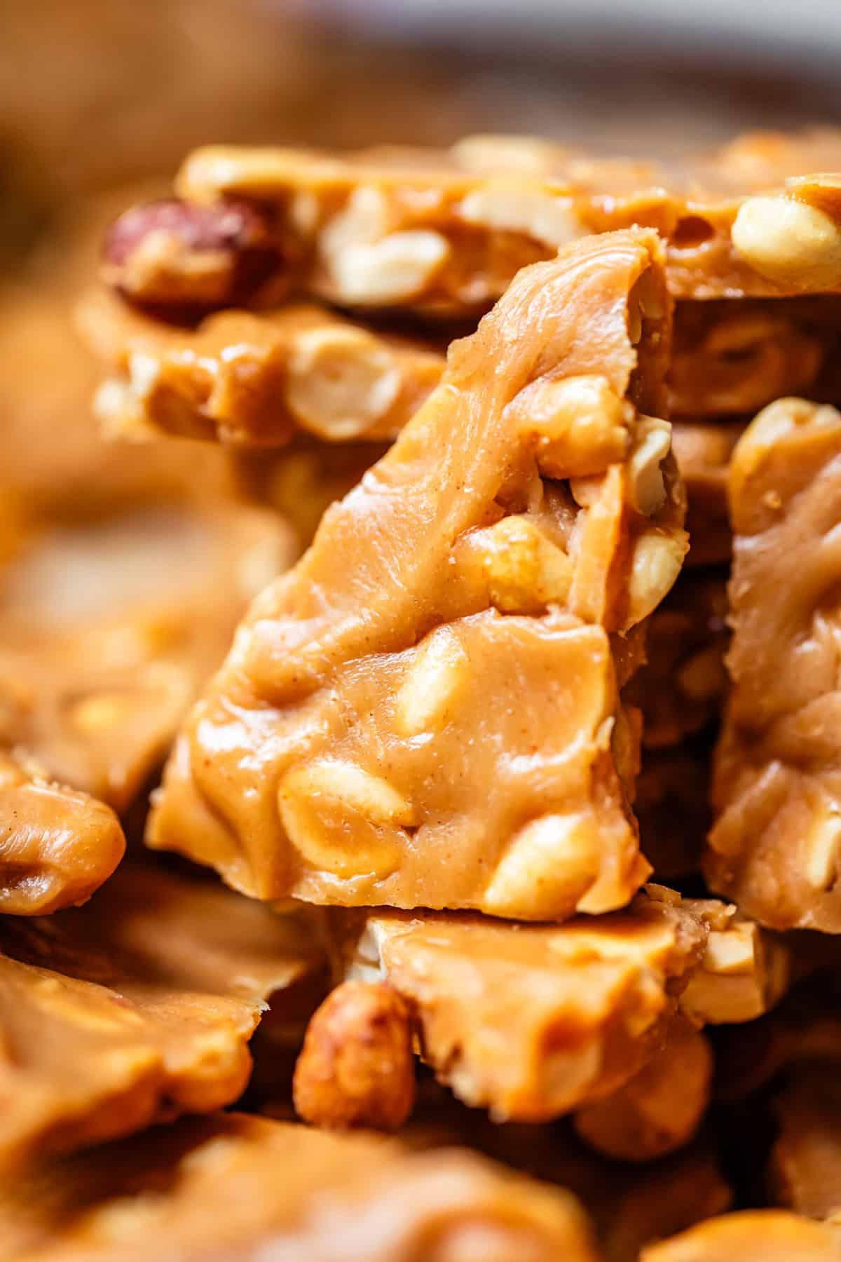 Close-up of a broken piece of peanut brittle showcasing its thinness and crisp texture