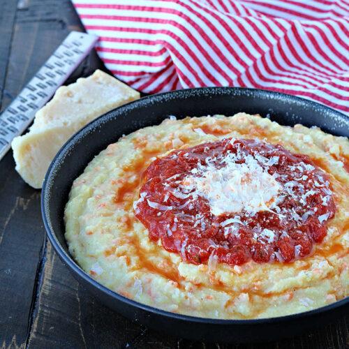 A close-up shot of the prepared cauliflower rice polenta with roasted tomatoes in a skillet.