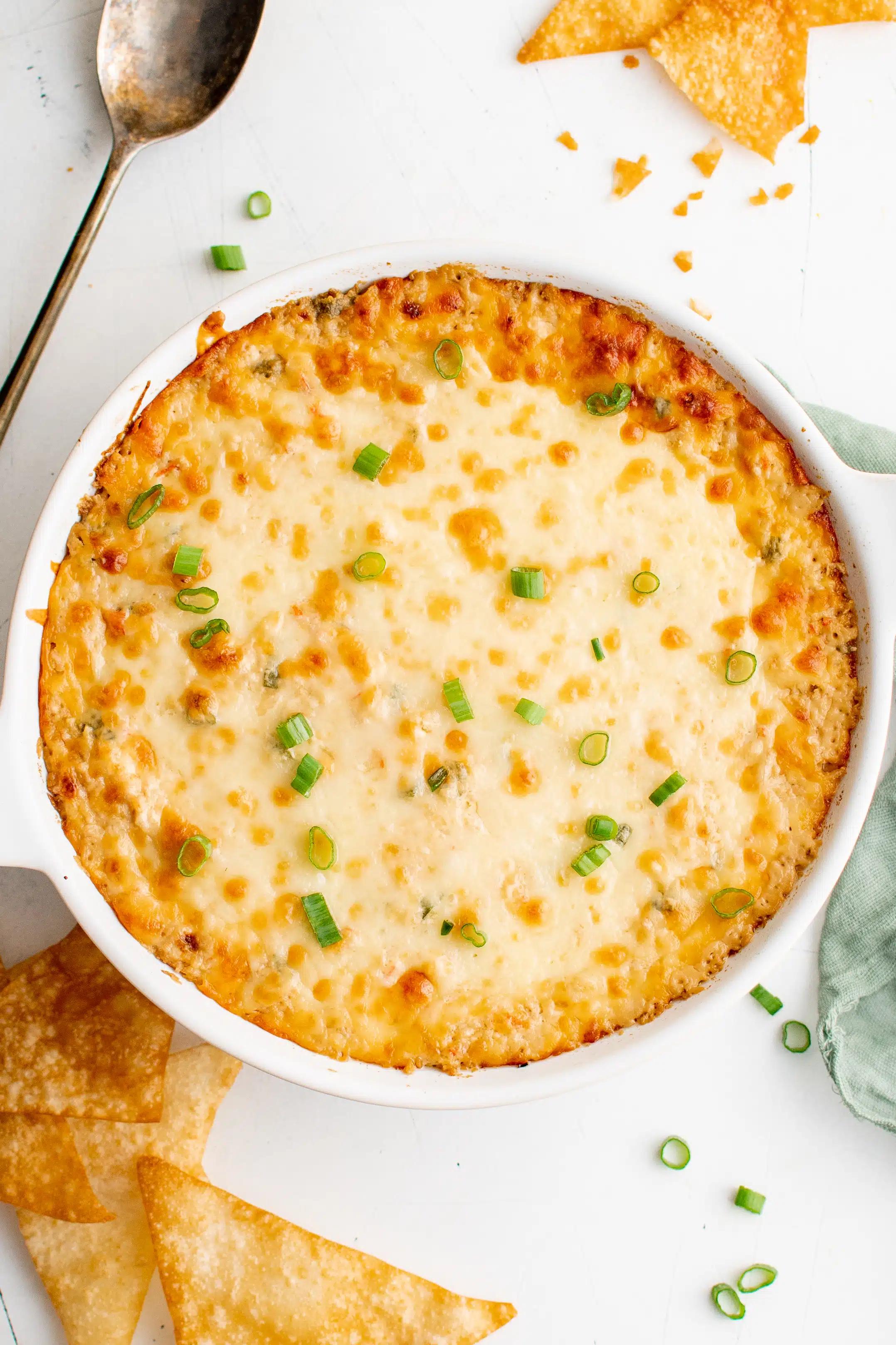 close up of a spoonful of crab rangoon dip being scooped out of a baking dish