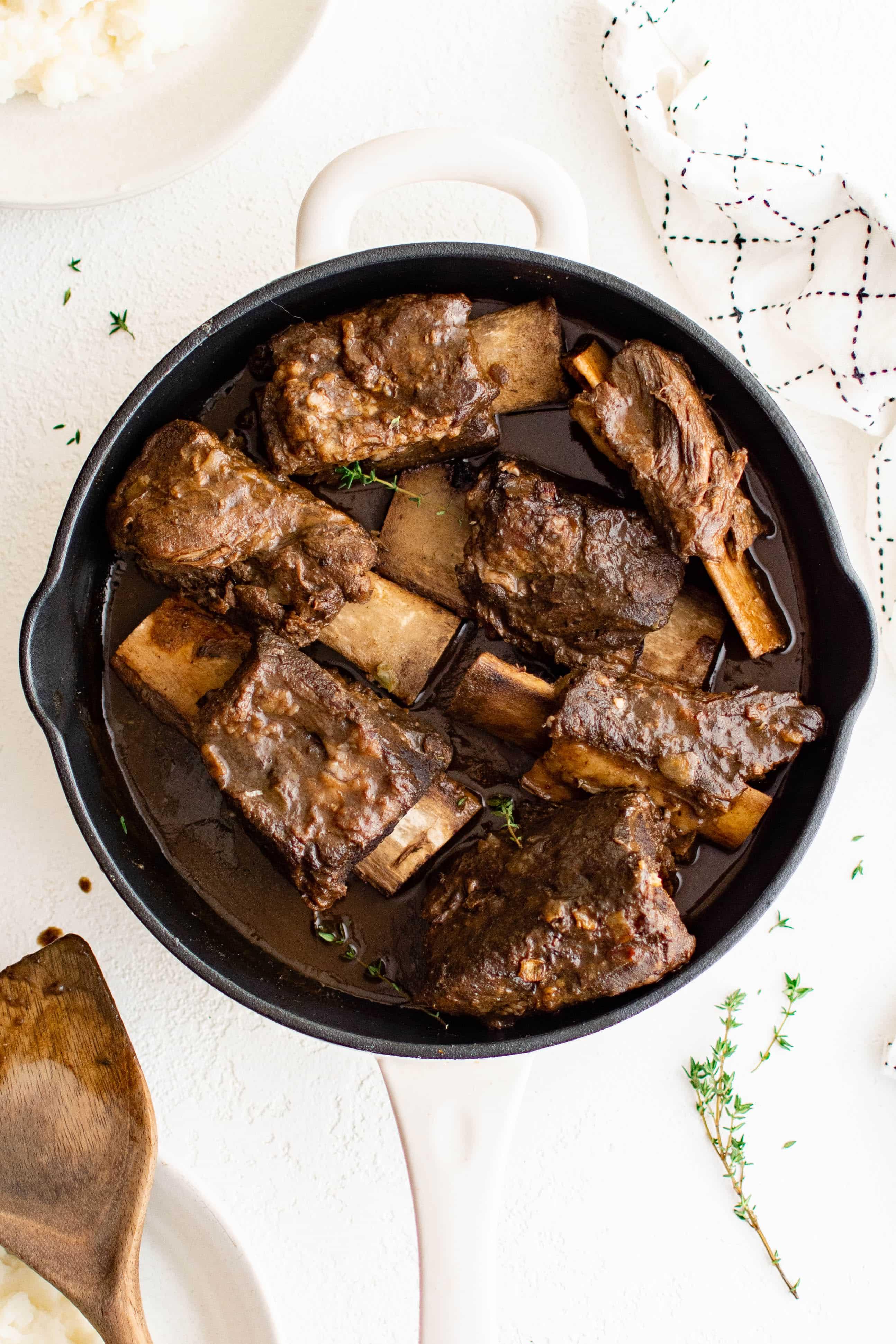 Dutch oven filled with short ribs braising in Champagne sauce, bubbling gently