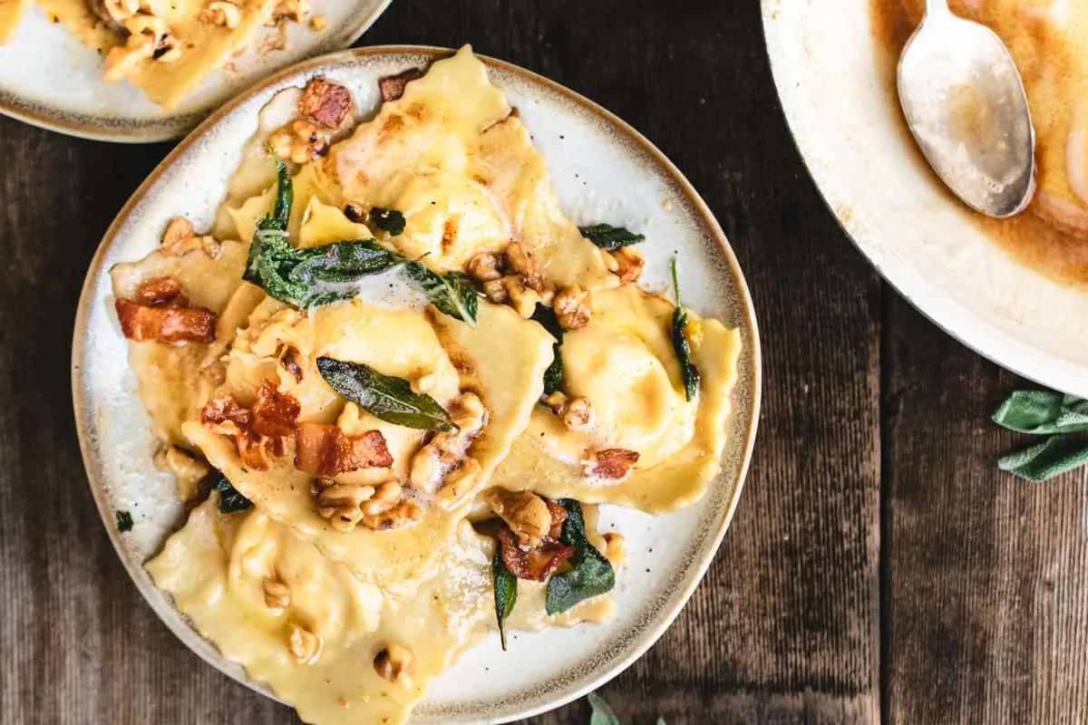 Butternut squash ravioli with sage butter sauce, garnished with parmesan and toasted walnuts