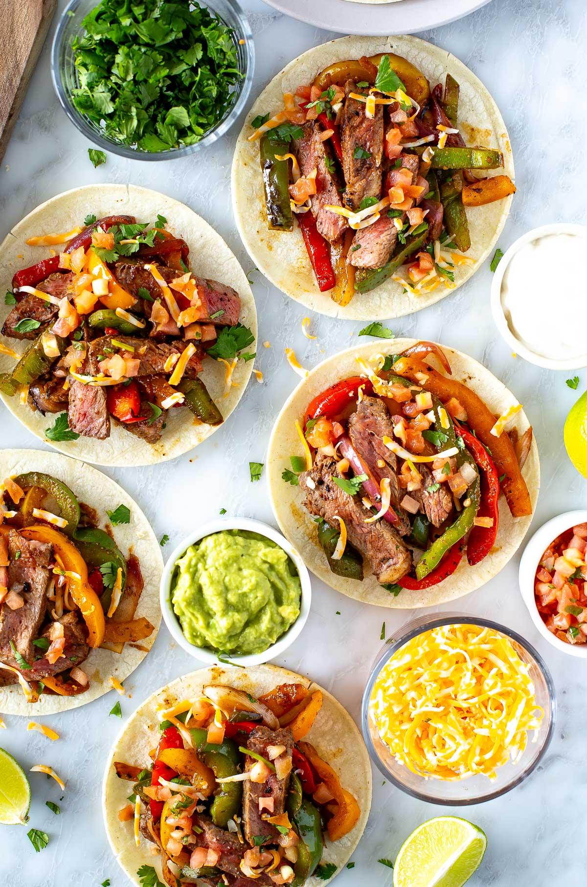 various toppings for fajitas, like sour cream, guacamole, salsa, and lime wedges