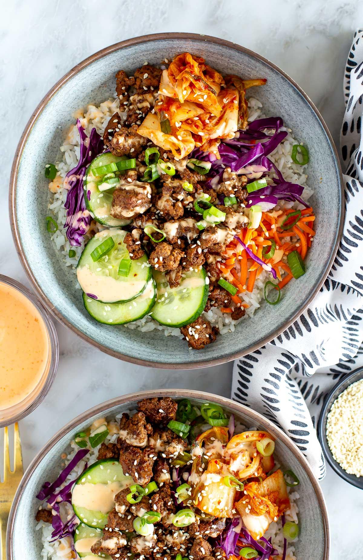 Overhead shot of a colorful chili-glazed beef bowl with various toppings