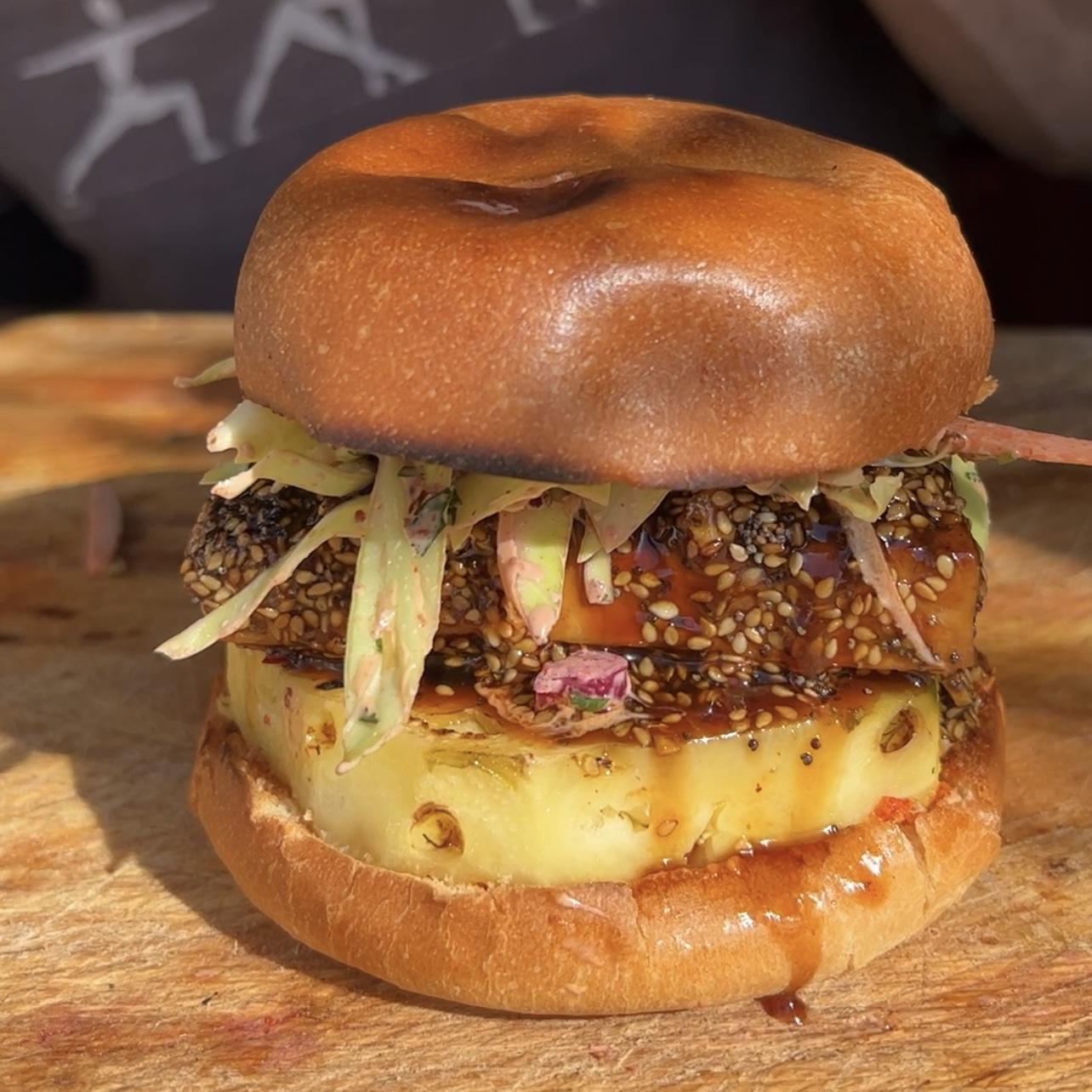 Kimchi Tofu Burger on a wooden cutting board with sesame seeds