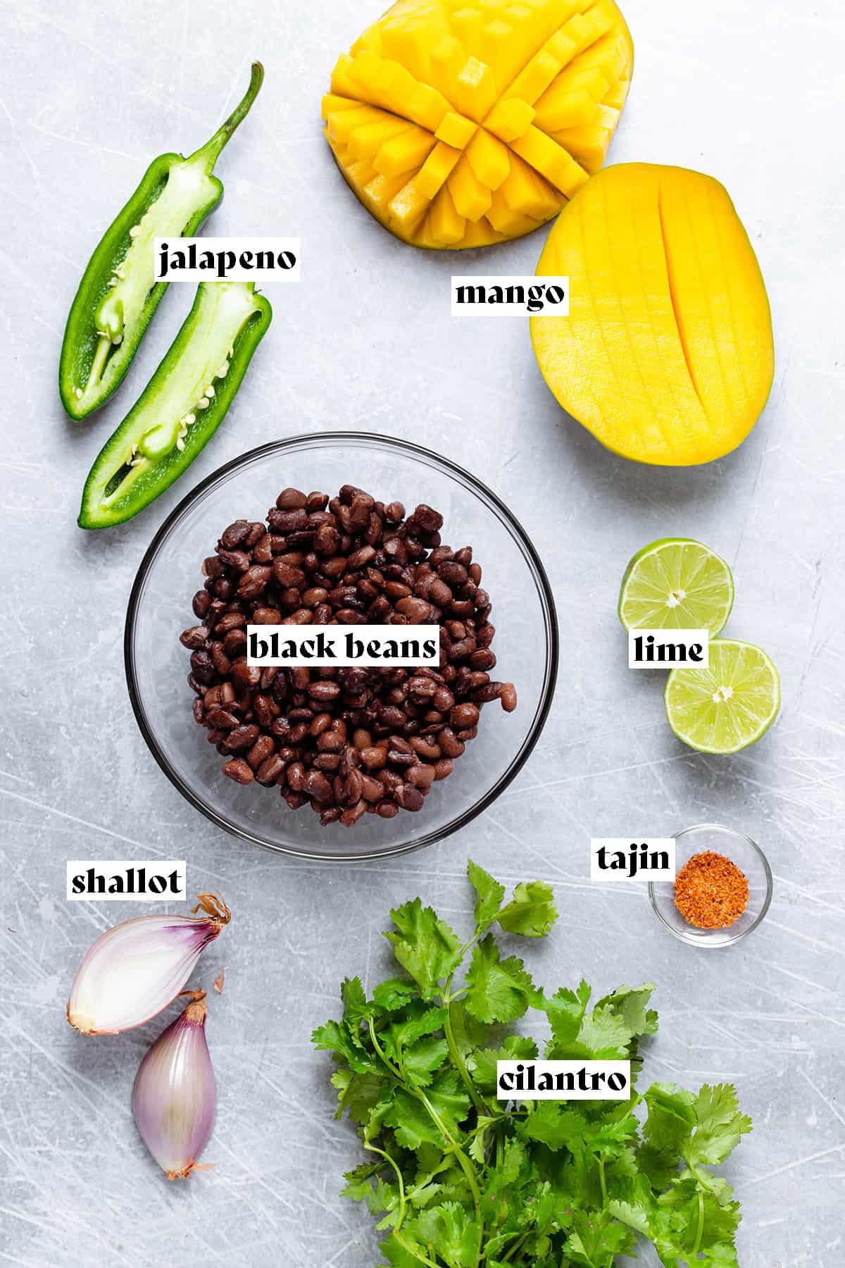 ingredients for black bean and mango salsa laid out on a wooden cutting board