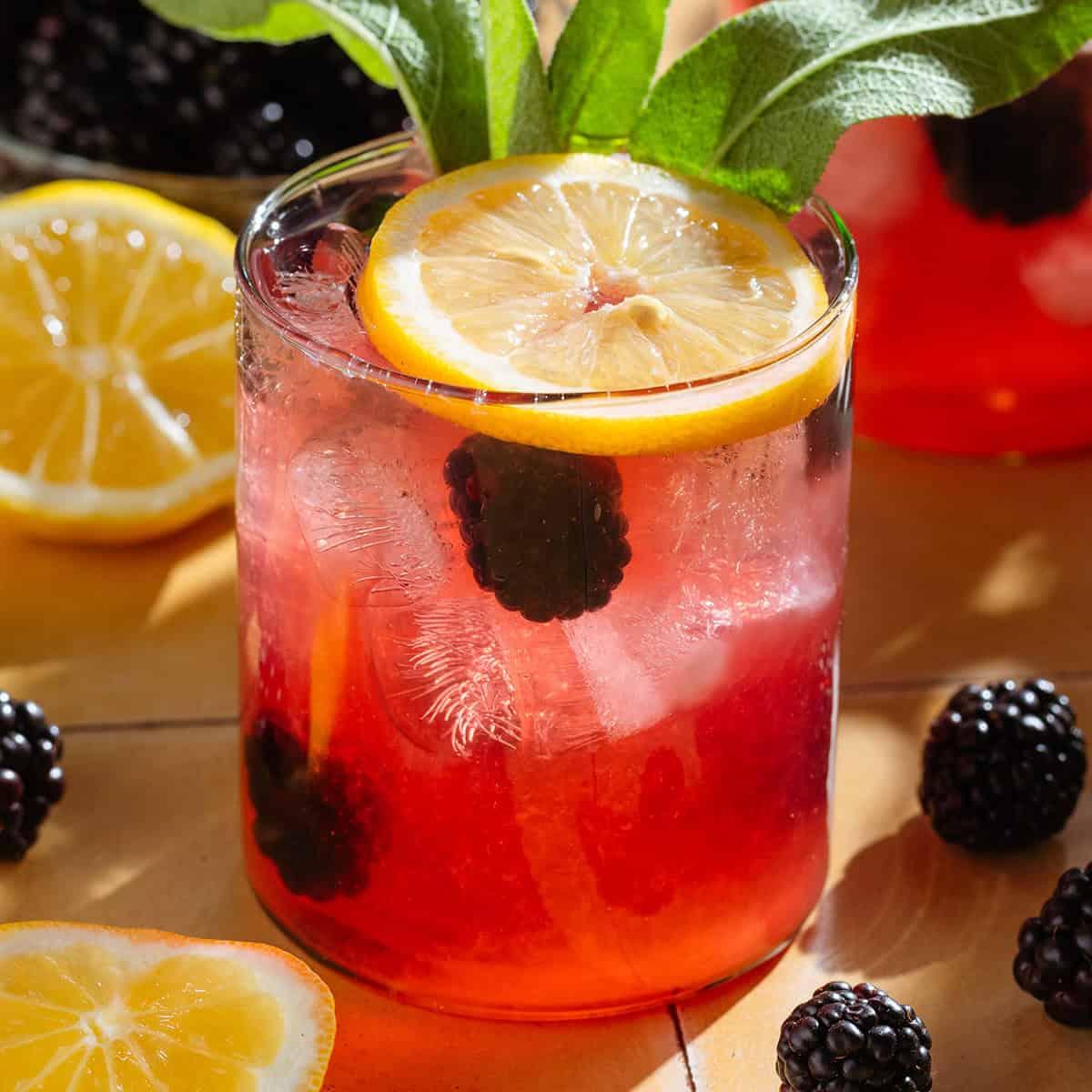 pitcher of blackberry sage lemonade with ice and lemon slices
