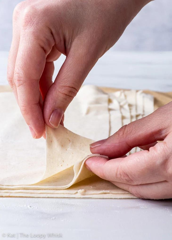 Close up of hands carefully layering phyllo dough