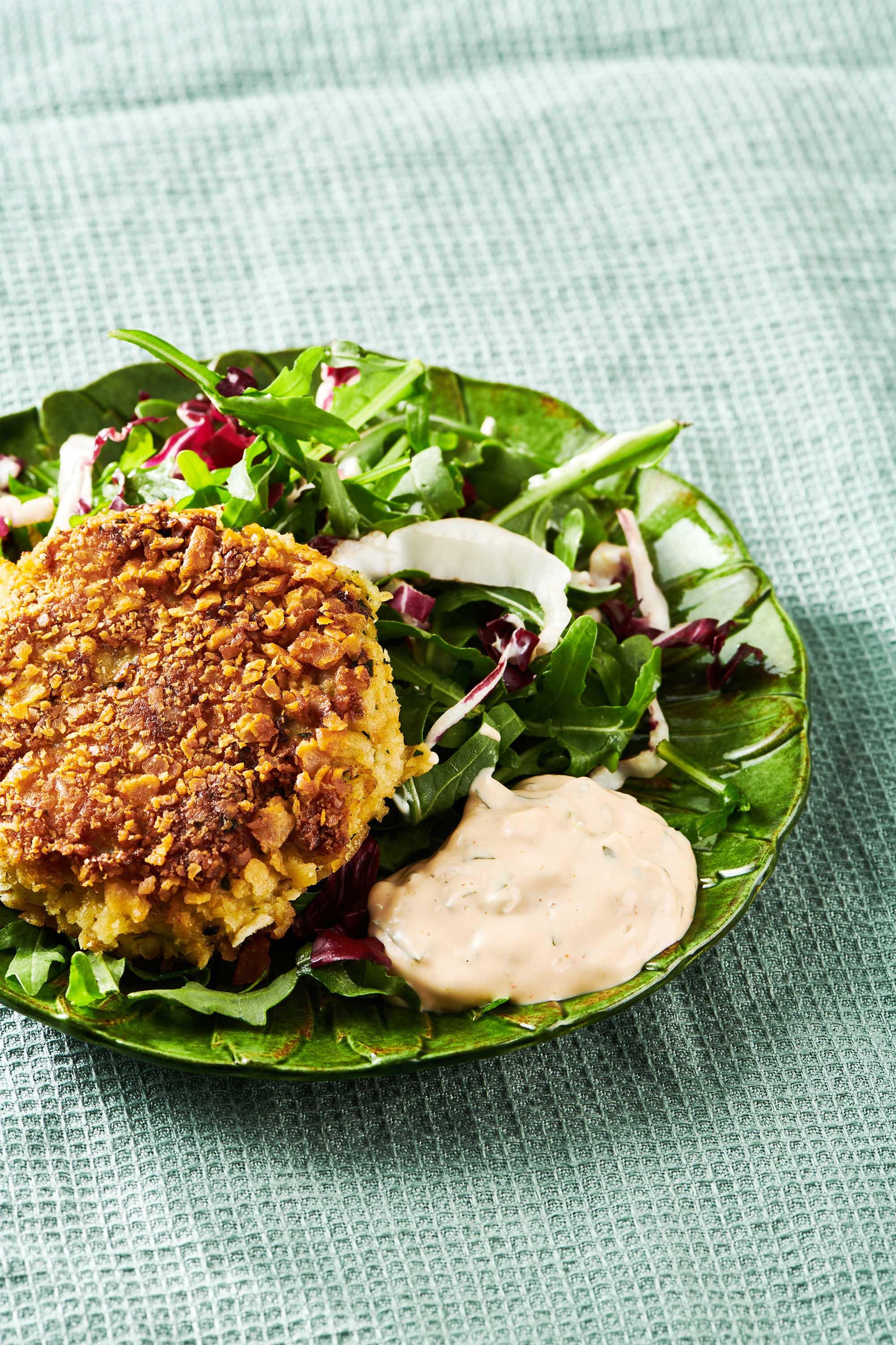 remoulade sautéed crab cakes on a plate with a fresh green salad
