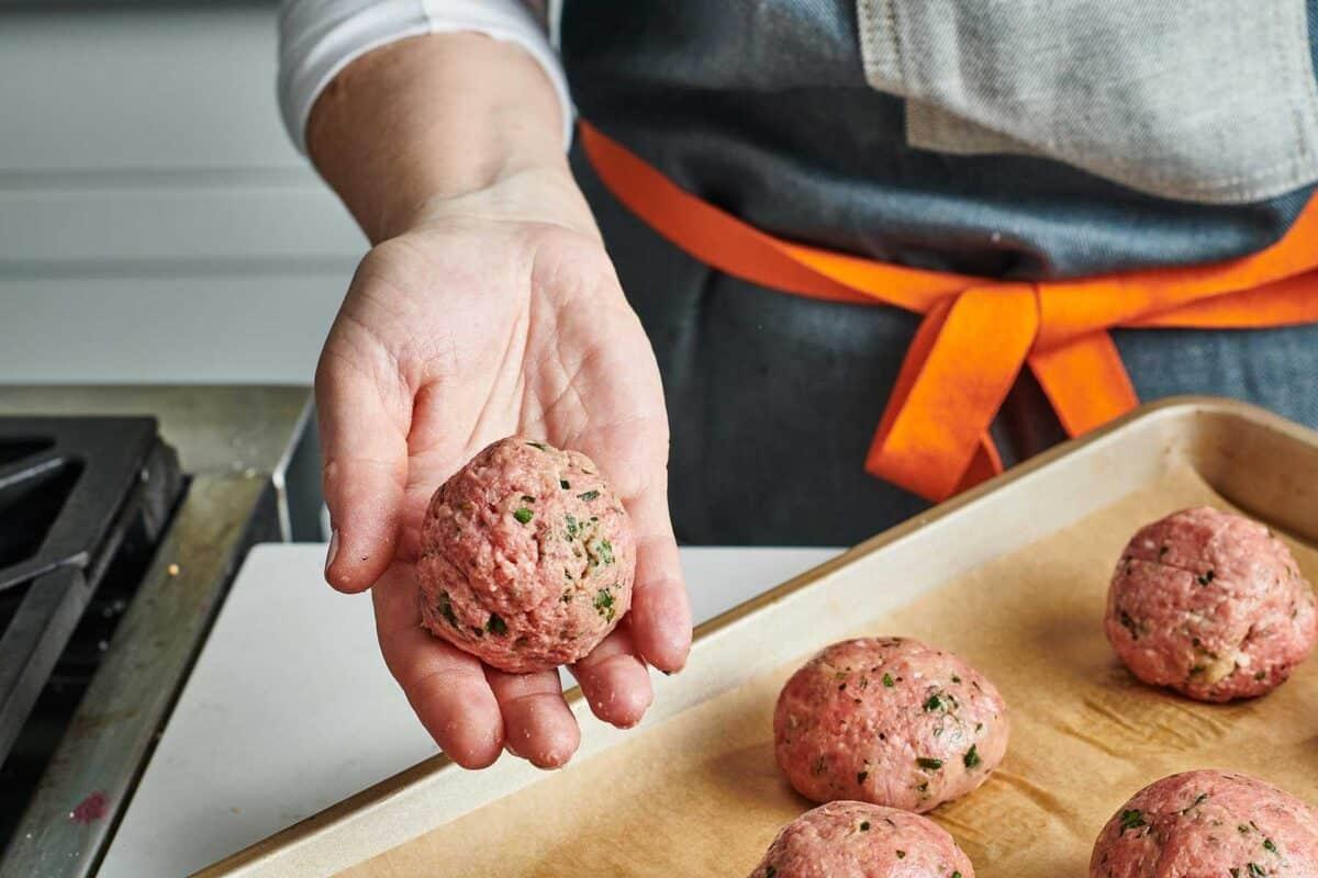 close-up shot of tiny meatballs being rolled by hand